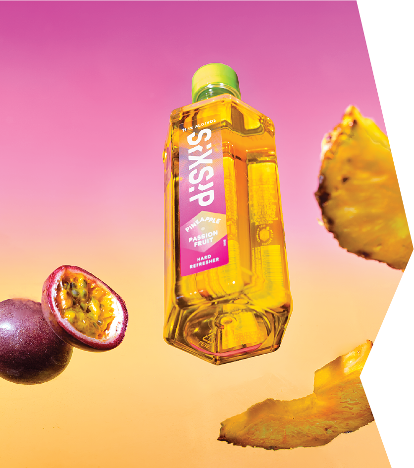 bottle photo from the bottom up against a gradient background surrounded by fruit